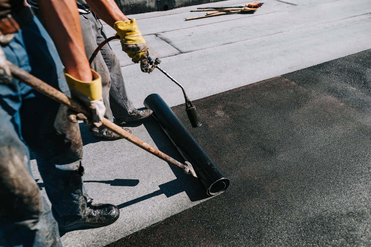 Bituminous membrane waterproofing system details and installation on flat rooftop. Professional construction worker  installing and waterproofing flat roof at house construction site.